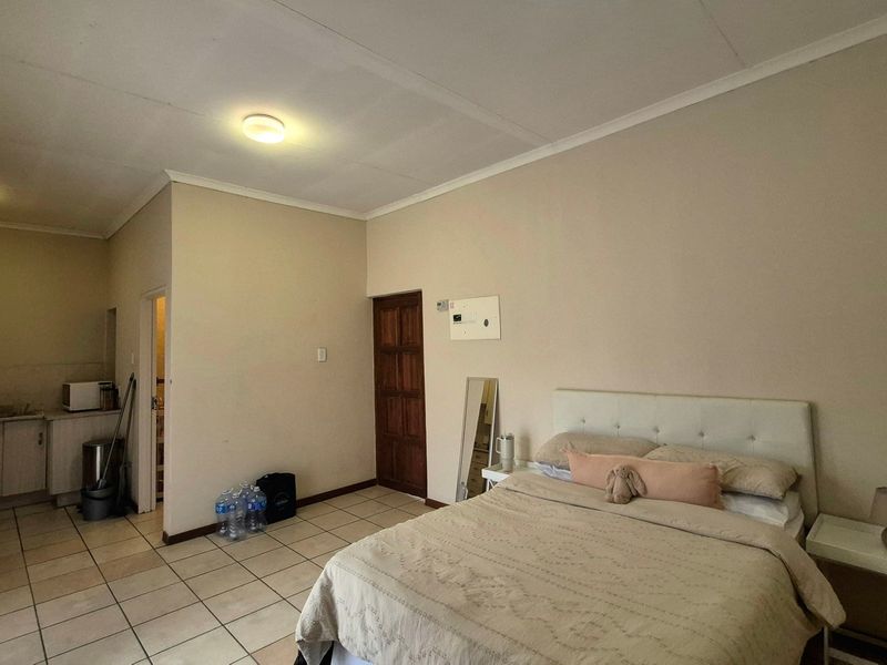 Open-plan studio apartment featuring tiled flooring, a compact kitchenette with built-in cabinetry, and a combined living and sleeping area.