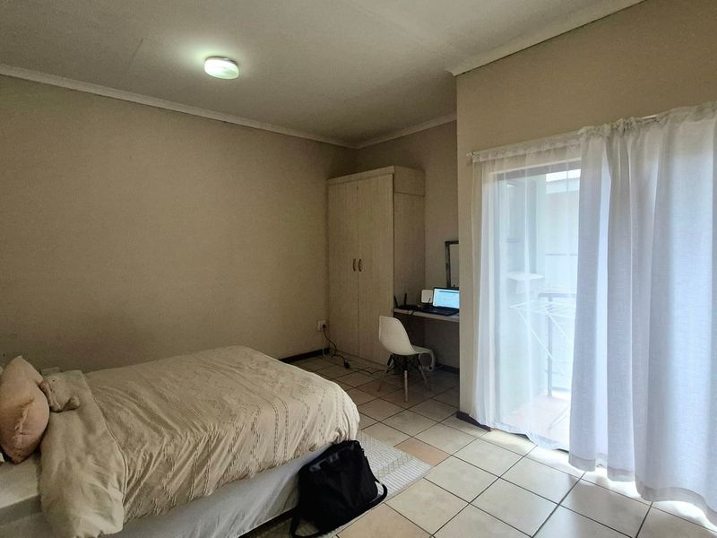 A bedroom featuring tiled flooring, a built-in wardrobe, and a sliding glass door providing access to an outdoor area.
