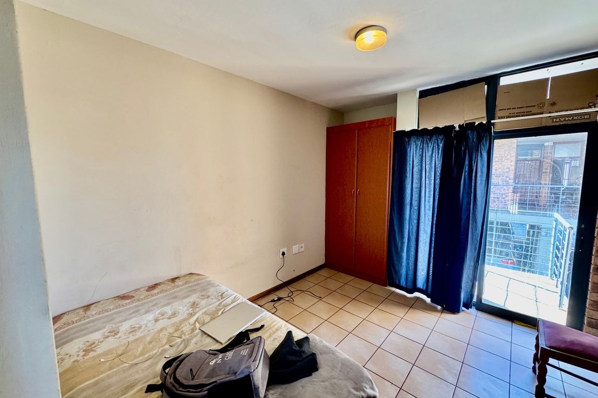 A bedroom featuring tiled flooring, a built-in wardrobe, and a sliding glass door providing access to a balcony.