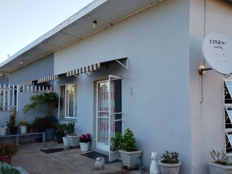 Front exterior view of the townhouse featuring a paved entrance area, security gate, and installed satellite dish.