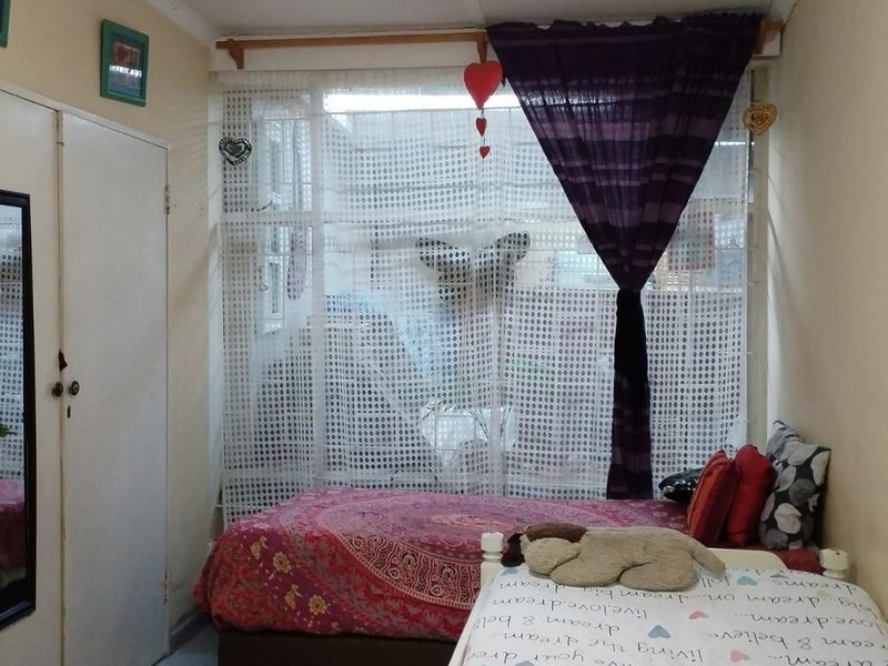 A bedroom featuring a built-in wardrobe and a large window that provides natural light to the space.