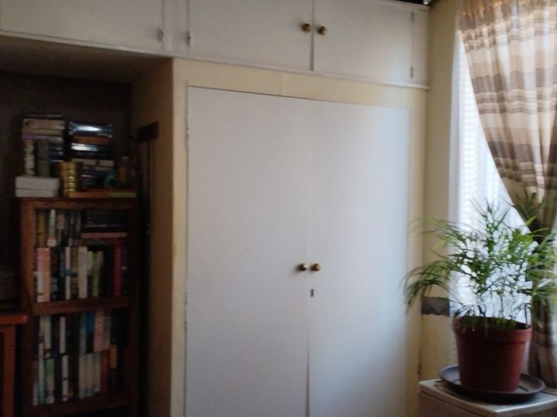 A bedroom featuring built-in wardrobes with overhead storage cupboards, providing functional storage space within the room.