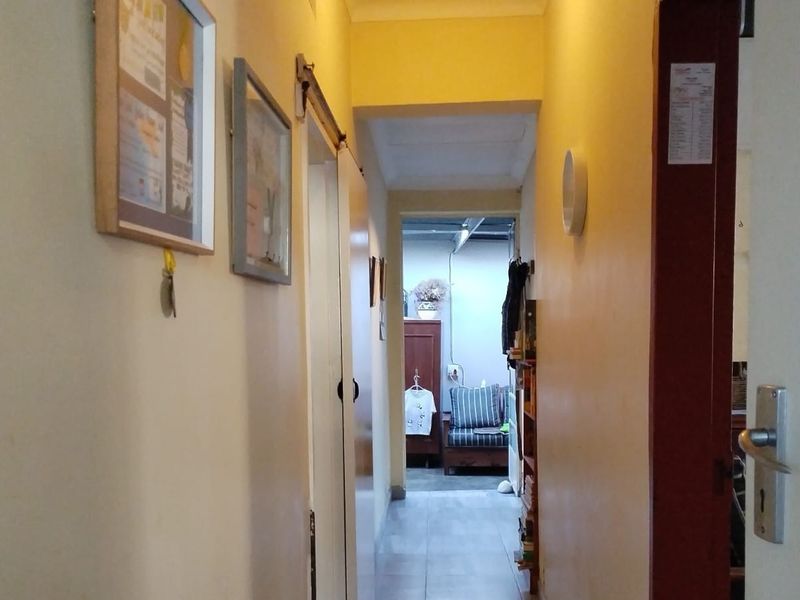 A narrow interior hallway connecting living spaces, featuring neutral wall finishes and laminate flooring.