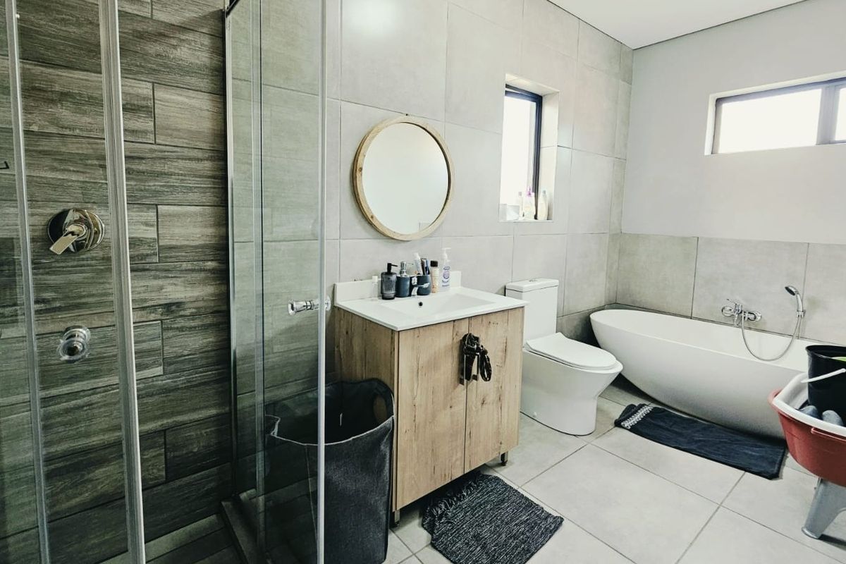 Modern bathroom featuring a glass-enclosed shower, a sleek freestanding bathtub, a vanity cabinet with a basin, and contemporary wall and floor tiling.