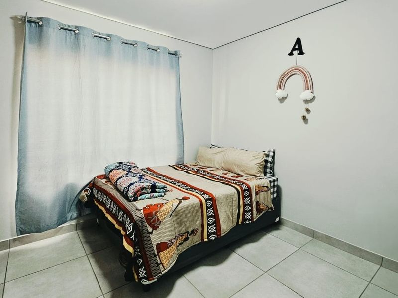 A well-maintained bedroom featuring neutral tiled flooring and a built-in wardrobe, offering a clean and functional living space.