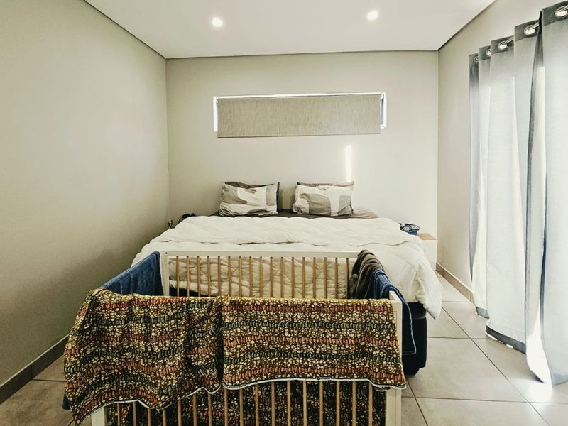 A well-maintained bedroom featuring neutral wall tones, tiled flooring, recessed lighting, and a sliding glass door providing access to the exterior.