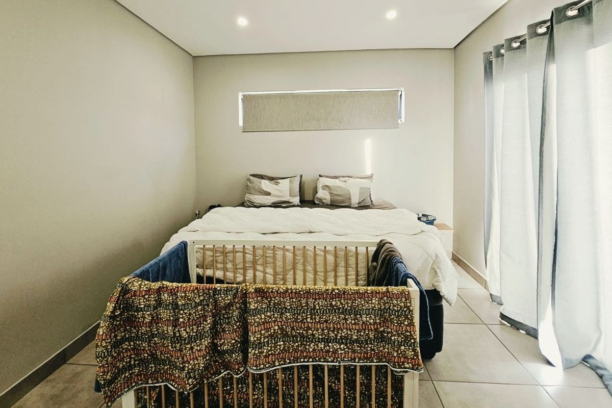 A well-maintained bedroom featuring neutral wall tones, tiled flooring, recessed lighting, and a sliding glass door providing access to the exterior.