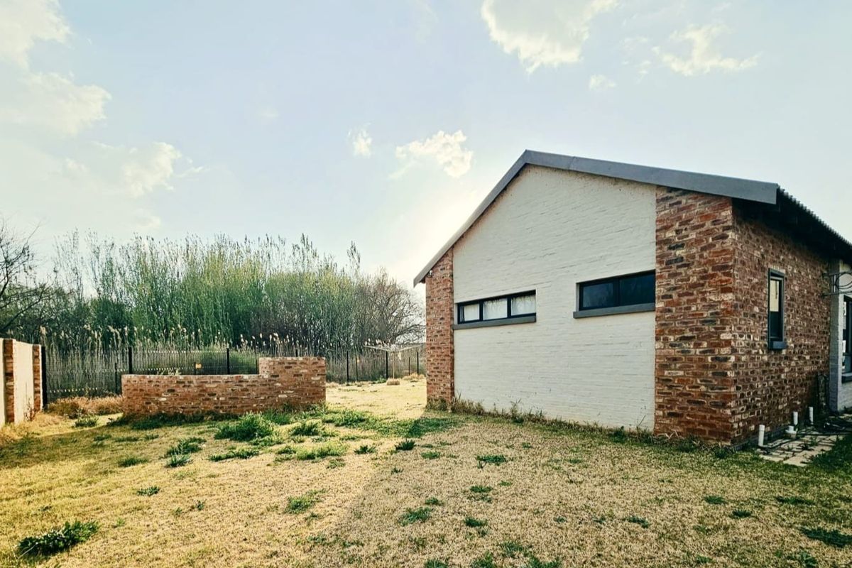 Rear view of the property featuring a combination of brick and painted masonry walls, horizontal windows, and a private garden area.