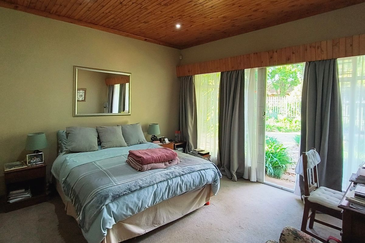 Spacious bedroom featuring a warm timber ceiling, carpeted flooring, and large sliding glass doors providing direct access to the garden.