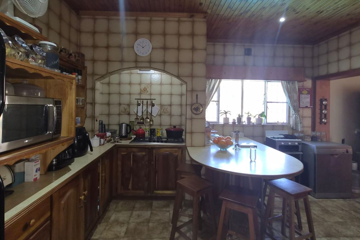 A traditional kitchen featuring wooden cabinetry, a tiled backsplash, a timber ceiling, and a built-in breakfast bar area.
