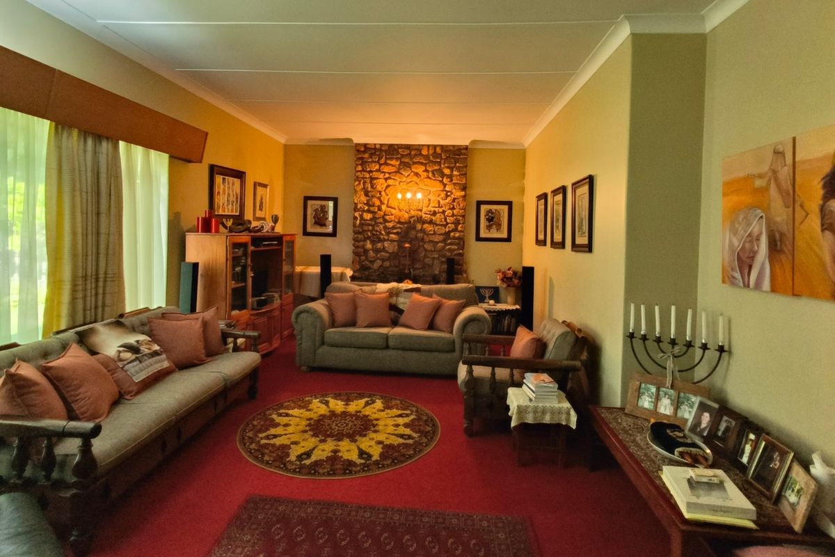 A spacious living room featuring a prominent stone fireplace, neutral wall tones, and large windows allowing for natural light.