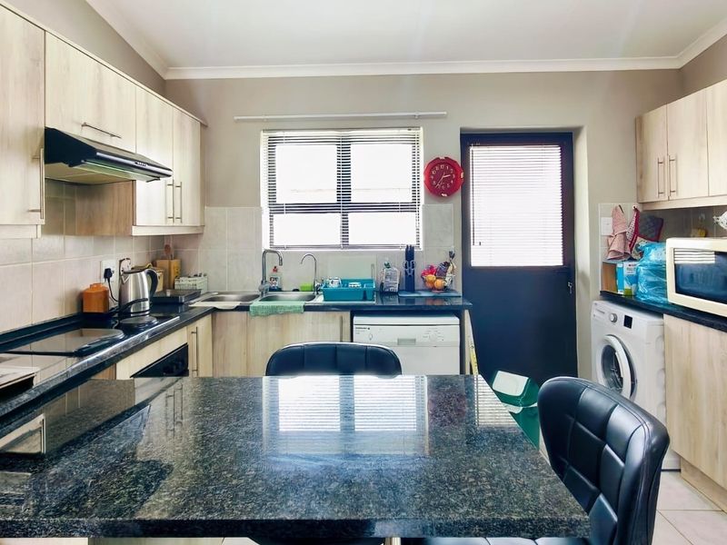 Functional kitchen featuring granite countertops, light wood-finish cabinetry, built-in oven, extractor fan, and direct access to the exterior.