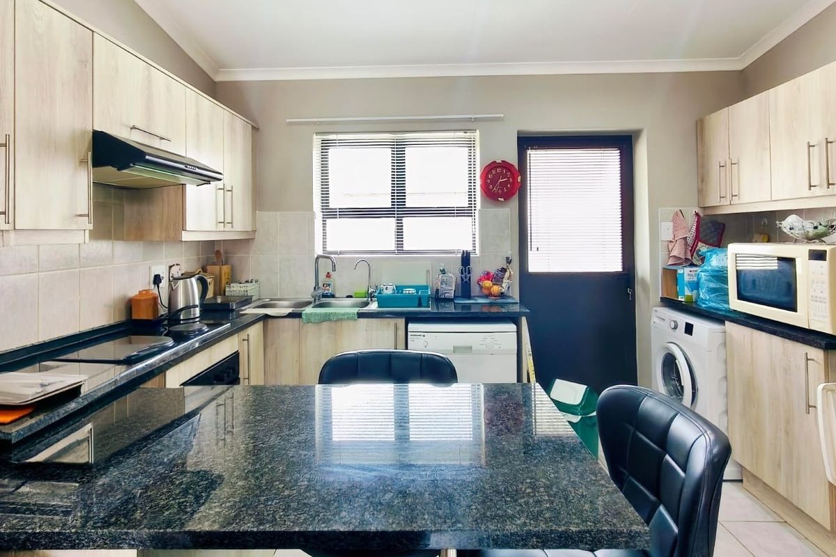 Functional kitchen featuring granite countertops, light wood-finish cabinetry, built-in oven, extractor fan, and direct access to the exterior.