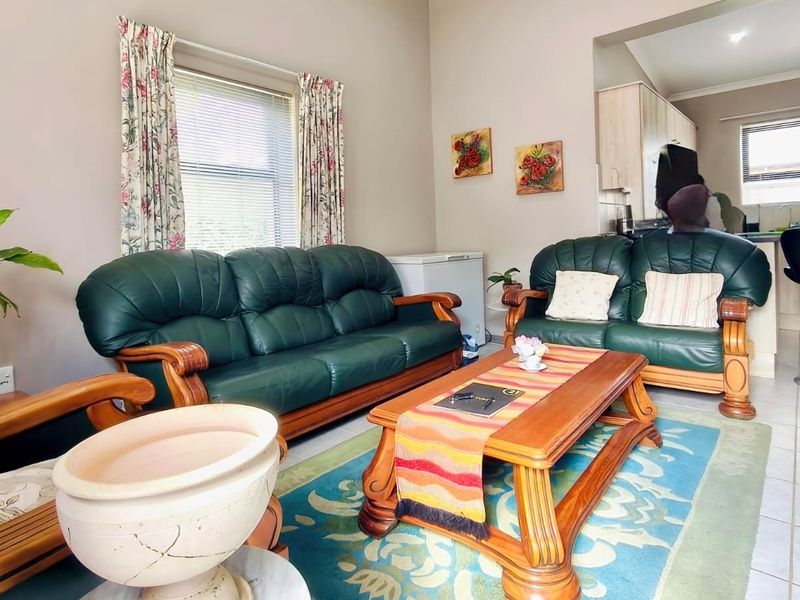 Open plan living area featuring tiled floors and a connected kitchen space with built-in cabinetry and countertops.