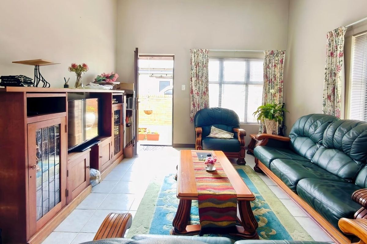 A bright living room featuring tiled flooring, large windows for natural light, and direct access to an outdoor area.