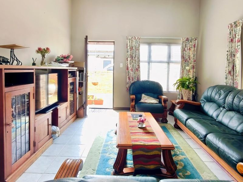 A bright living room featuring tiled flooring, large windows for natural light, and direct access to an outdoor area.