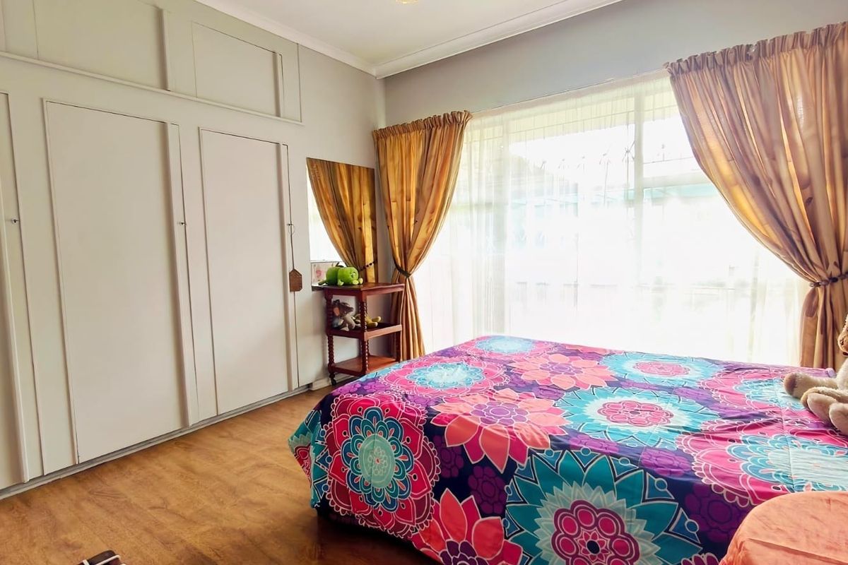 A bedroom featuring laminate flooring and extensive built-in cupboard storage with a large window allowing natural light.