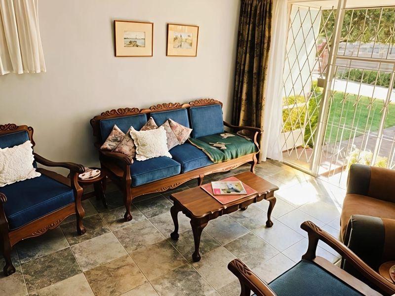 A living room featuring tiled flooring and a sliding glass door with security gate, providing access to the exterior.