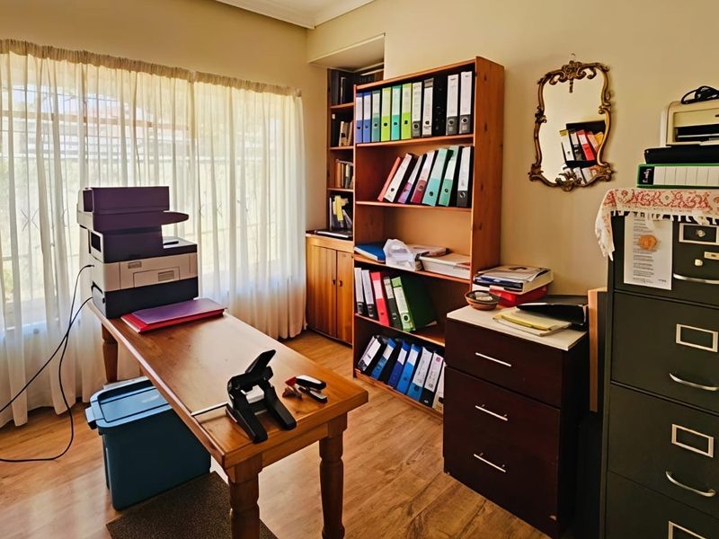 A functional home office space featuring laminate flooring and a built-in wooden shelving unit, providing ample storage and workspace.