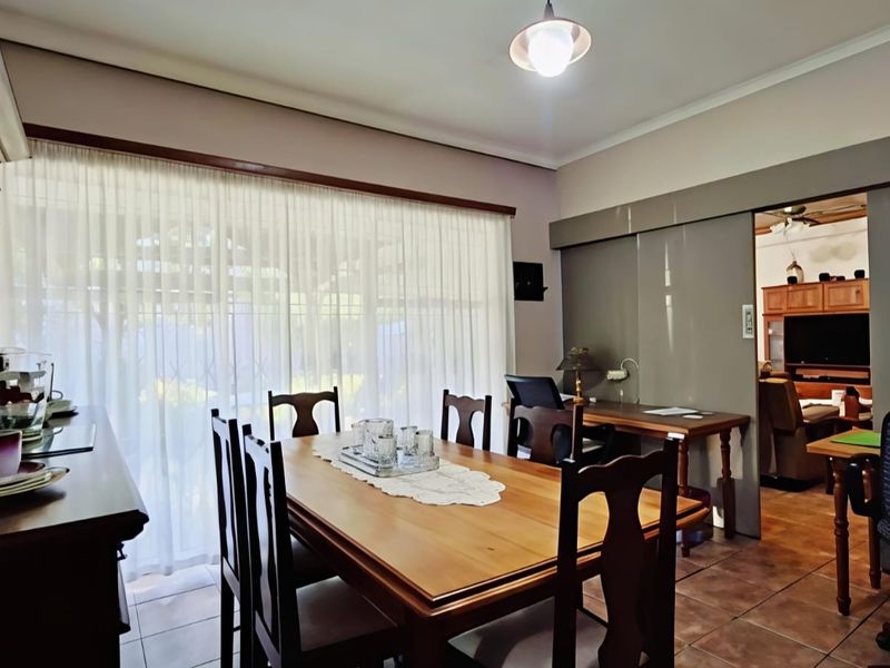 A dining room featuring tiled flooring, a large window with curtains, and a sliding door providing access to an adjacent living space.