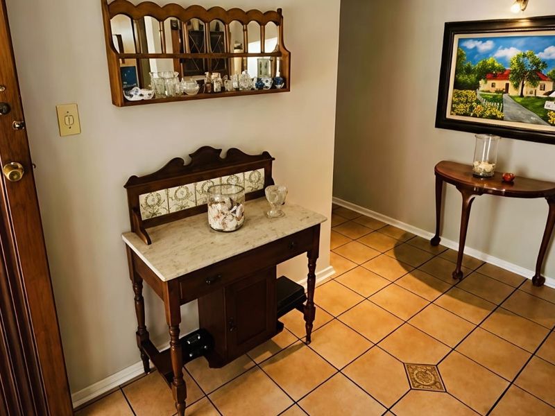 A welcoming entrance hall featuring classic ceramic tile flooring with a decorative inlay and a solid wood entry door.
