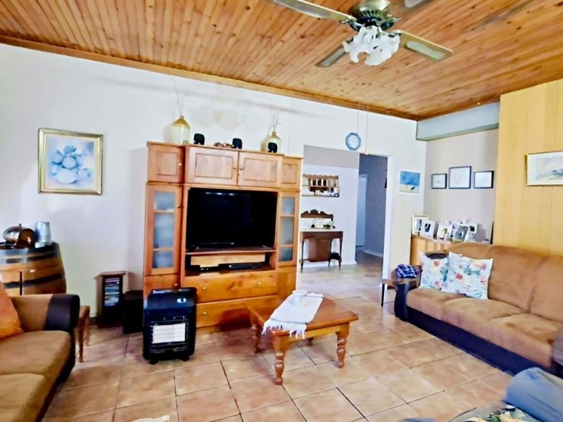 A living room featuring a timber ceiling with a ceiling fan, tiled flooring, and timber wall paneling accents.