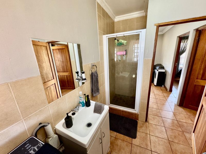 A functional bathroom featuring a vanity basin, shower enclosure, and tiled finishes, providing a practical layout for daily use.