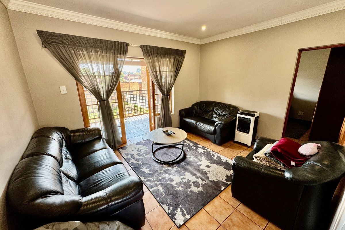 A living room featuring tiled flooring, crown molding, and a sliding glass door providing access to an outdoor balcony area.