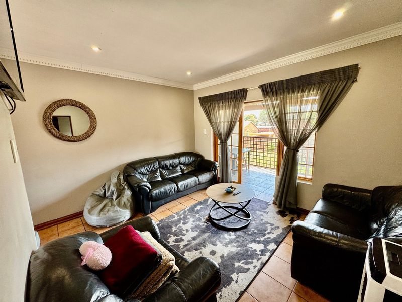 A comfortable living room featuring tiled flooring, recessed lighting, and direct access to an outdoor balcony through sliding glass doors.