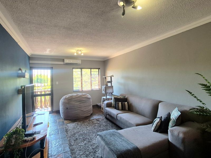 A living room featuring tiled flooring, a split-system air conditioner, and access to an outdoor area through a security gate.