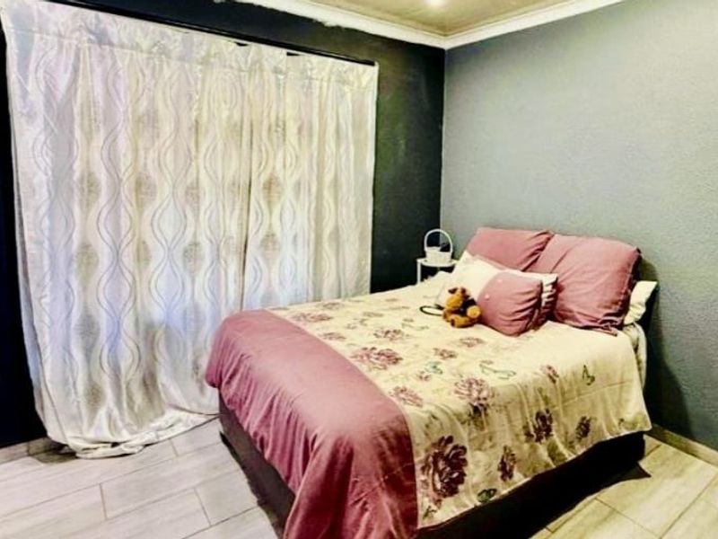 A bedroom featuring tiled flooring, a built-in wardrobe, and dark accent wall paint.