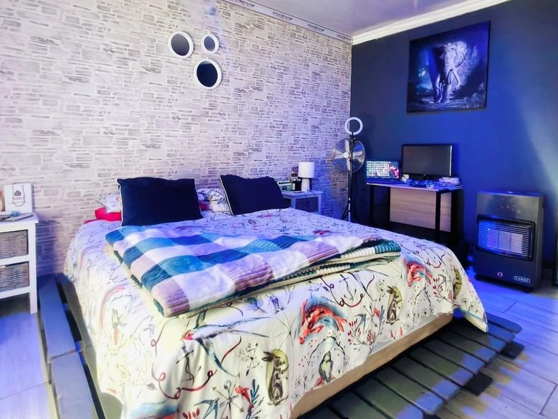 A bedroom featuring laminate flooring and a textured feature wall, providing a functional space with contemporary design elements.