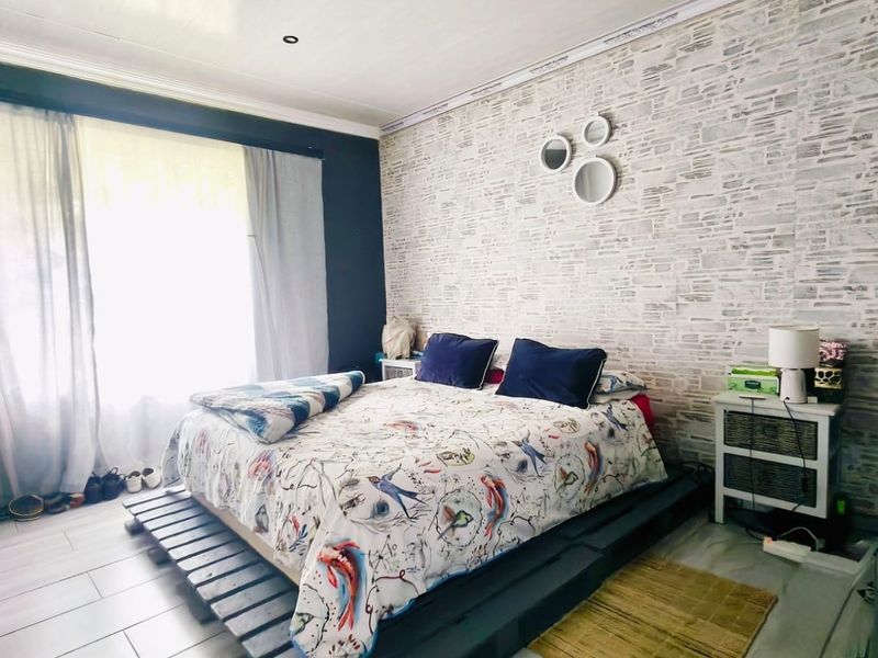 A bedroom featuring tiled flooring, recessed downlights, and a textured feature wall, providing a functional space with natural light.