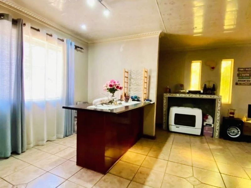 Open plan living area featuring tiled flooring, a built-in breakfast bar, and recessed ceiling lighting, offering a functional space for daily living.