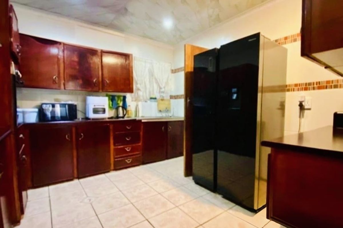 A functional kitchen featuring extensive wooden cabinetry, tiled flooring, and a tiled backsplash, offering a traditional layout with ample storage space.