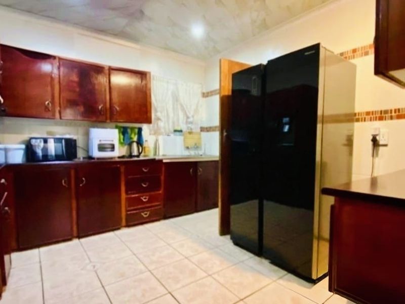 A functional kitchen featuring extensive wooden cabinetry, tiled flooring, and a tiled backsplash, offering a traditional layout with ample storage space.