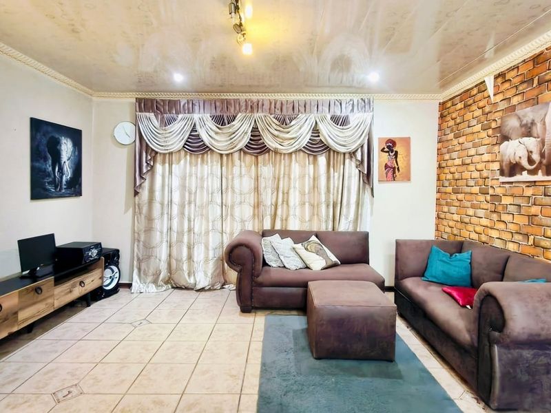 A living room featuring an exposed brick accent wall, tiled flooring, and a coved ceiling with recessed lighting.