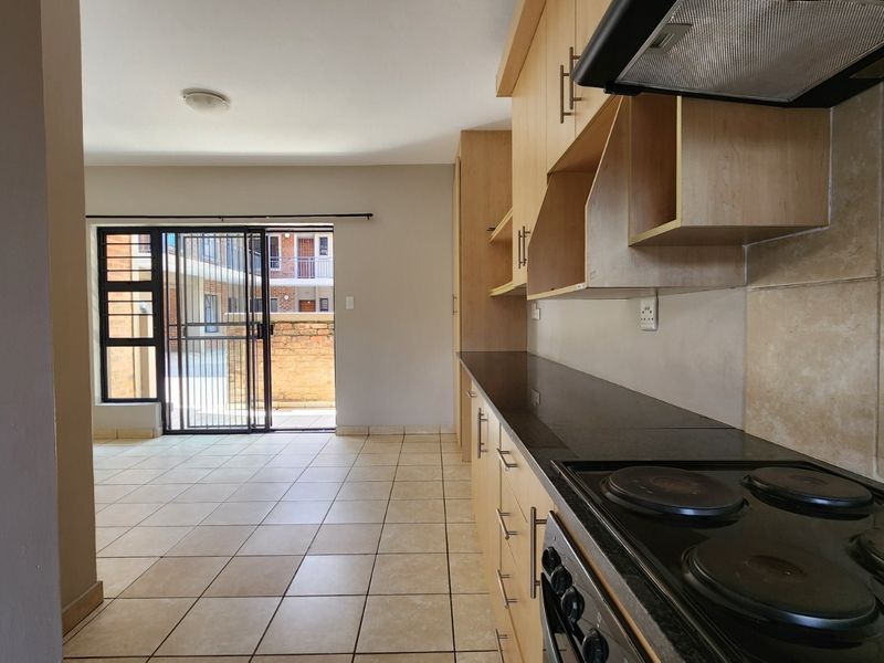 Open-plan kitchen and living area featuring tiled floors, built-in cabinetry with granite countertops, and a sliding door leading to an outdoor space.