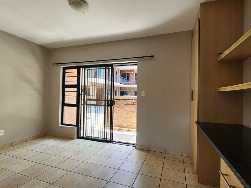 An open-plan living area featuring tiled floors, built-in cabinetry with shelving, and a sliding door providing access to an outdoor patio space.