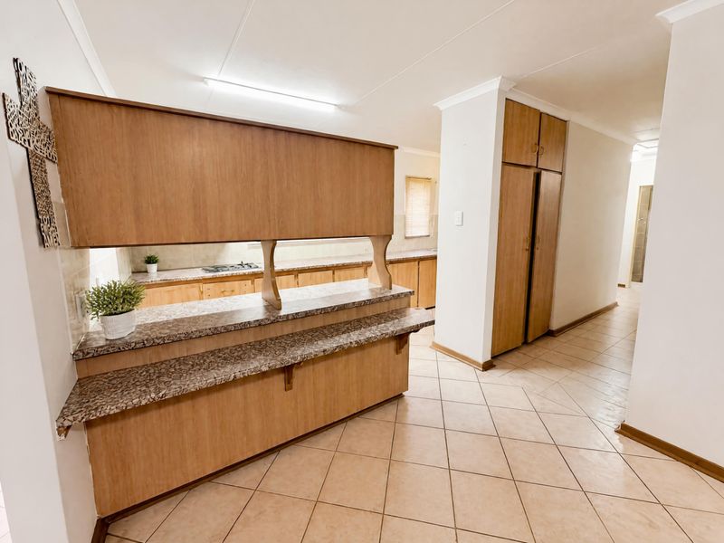 A functional kitchen featuring laminate cabinetry, stone-look countertops, a built-in hob, and tiled flooring, offering a clean and practical layout.