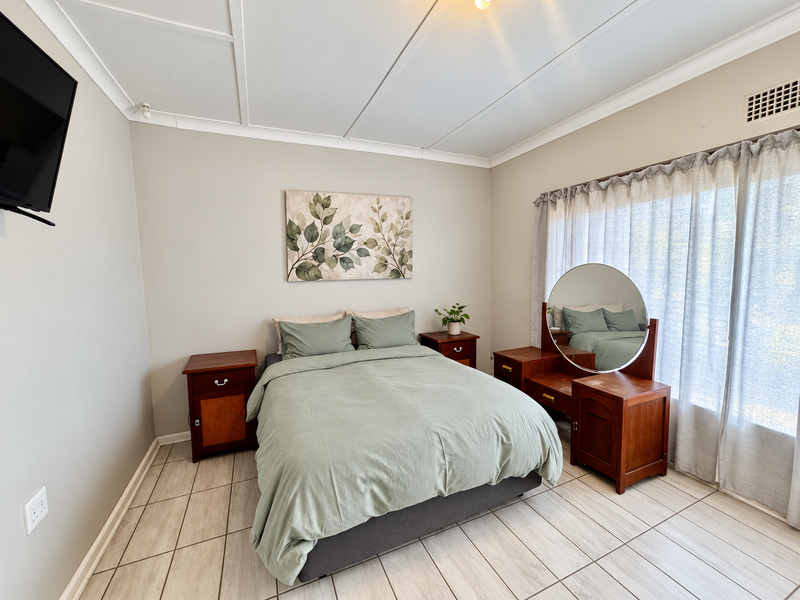 A well-maintained bedroom featuring neutral wall tones, tiled flooring, and a ceiling panel finish, offering a clean and functional living space.