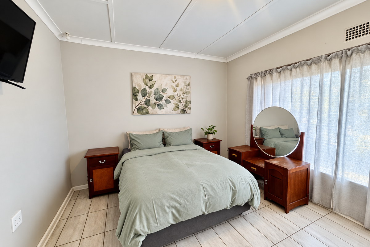 A well-maintained bedroom featuring neutral wall tones, tiled flooring, and a ceiling panel finish, offering a clean and functional living space.