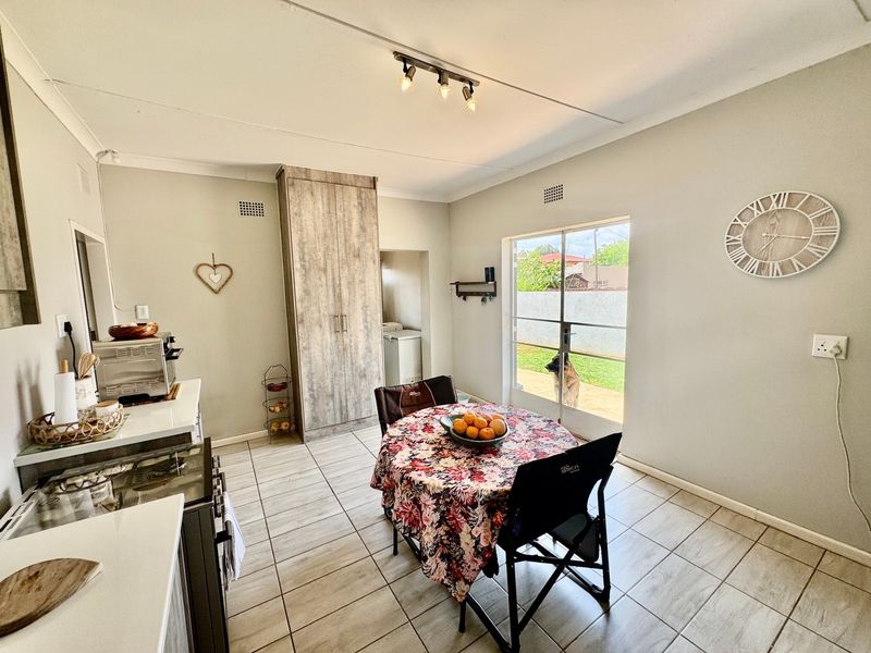 Open plan kitchen and dining area featuring tiled flooring, built-in cabinetry, and a sliding glass door providing access to the rear garden.