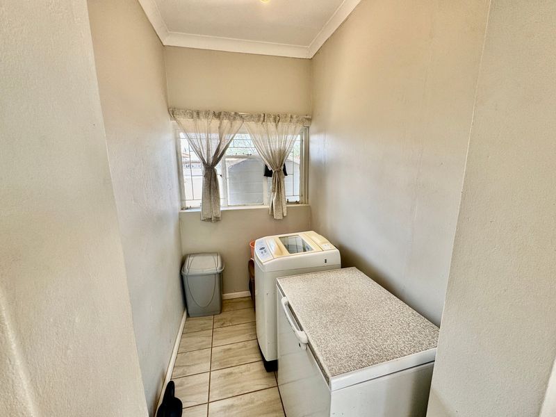 A functional laundry area featuring tiled flooring and a window, providing a dedicated space for utility and appliance placement.