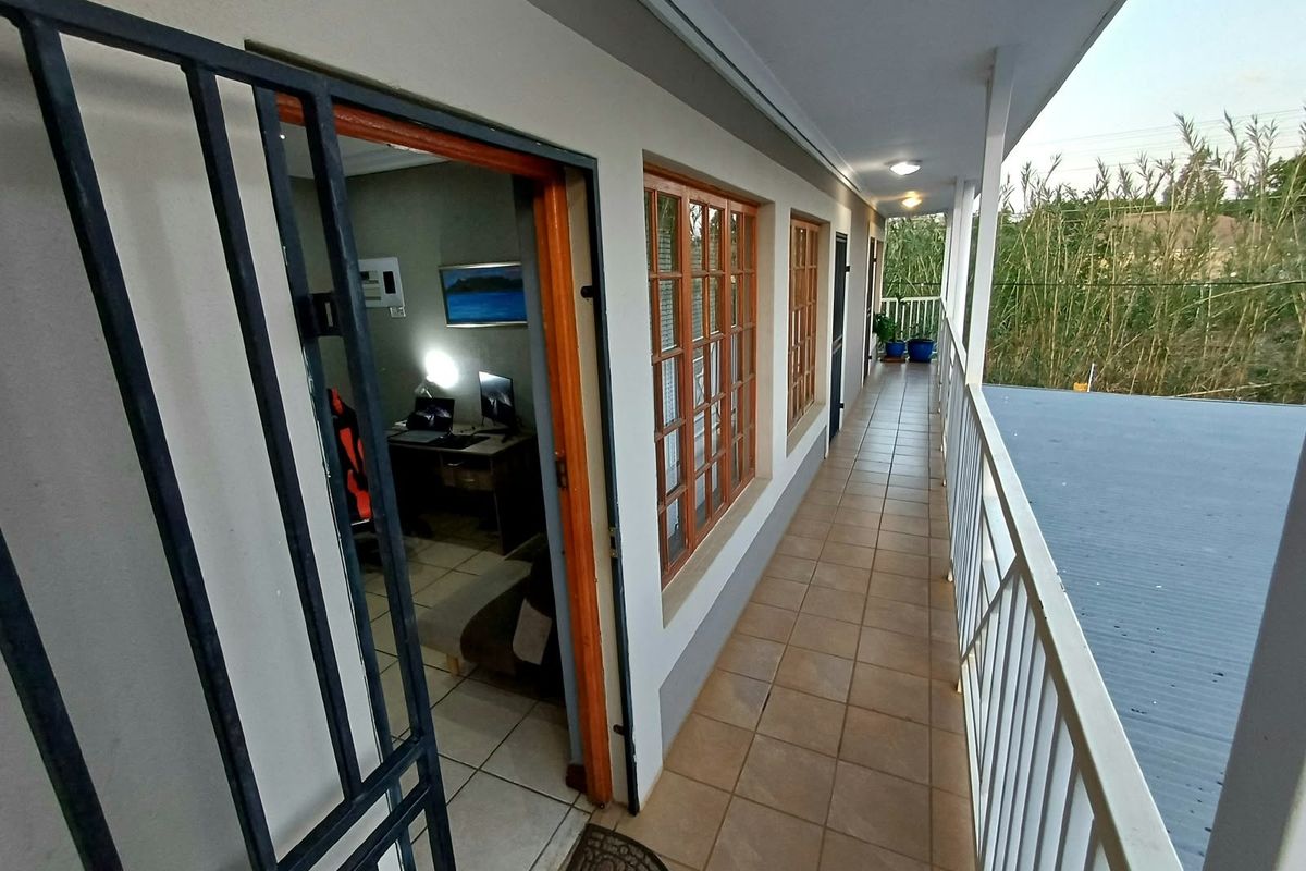 A covered balcony featuring tiled flooring, a metal security gate, and a protective balustrade, providing access to the interior living space.
