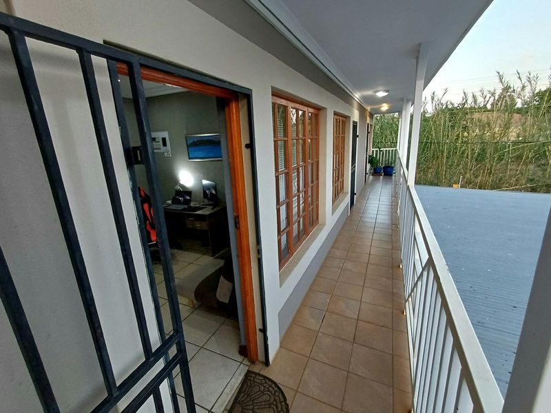 A covered balcony featuring tiled flooring, a metal security gate, and a protective balustrade, providing access to the interior living space.