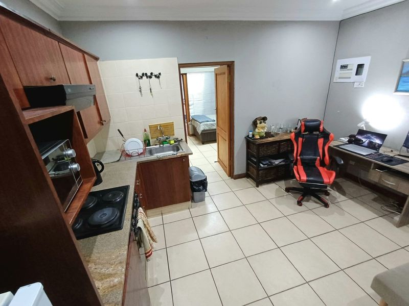 Open-plan kitchen and living area featuring tiled flooring, built-in cabinetry, electric hob, and a dedicated built-in desk space.
