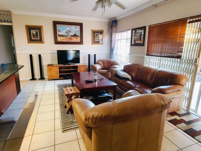 Open plan living area featuring tiled flooring, a ceiling fan, and sliding glass doors providing access to the outdoor patio area.