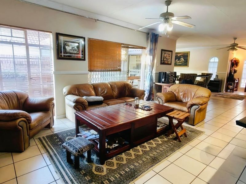 Spacious open-plan living area featuring tiled flooring, ceiling fans, and large windows with blinds, providing a functional and connected layout for the home.