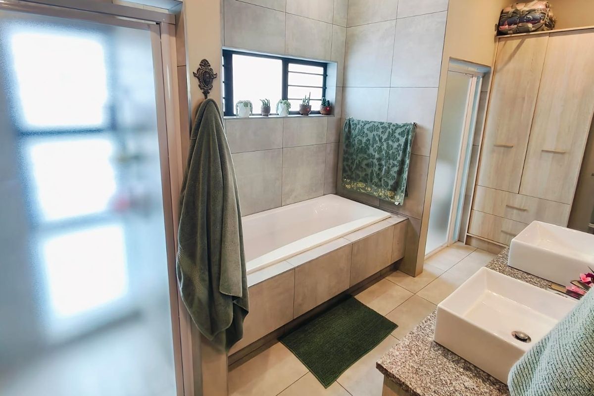 Modern bathroom featuring a built-in bathtub, dual vessel sinks with granite vanity, and neutral tiled finishes throughout.